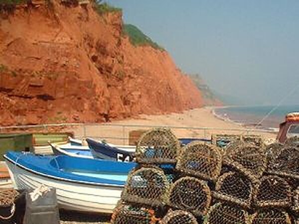 Fishing boats and lobster pots on Sidmouth beach beneath the red cliffs